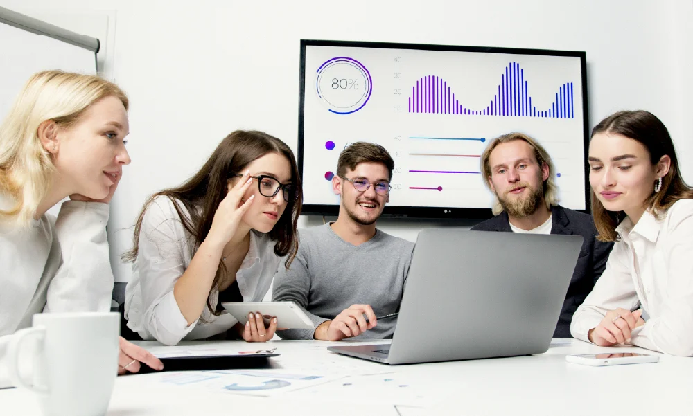 Equipo de trabajo analizando métricas de protección financiera y opciones de seguros de vida en una pantalla y laptop.