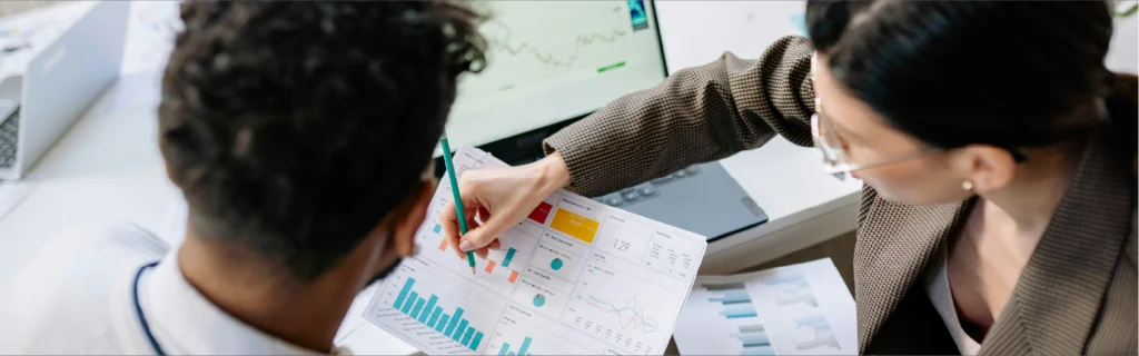 Dos profesionales jóvenes analizando gráficas financieras y métricas de crecimiento para construir patrimonio.