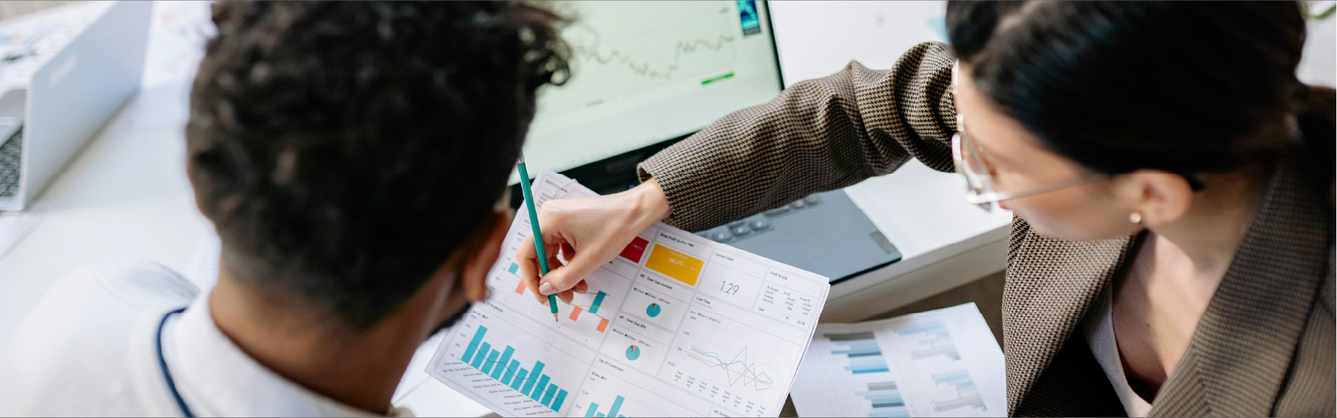 Dos profesionales jóvenes analizando gráficas financieras y métricas de crecimiento para construir patrimonio.