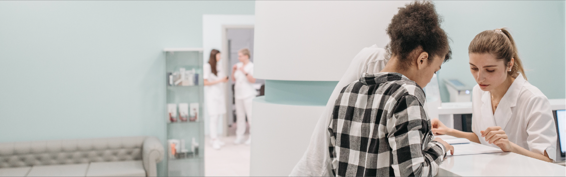 Paciente joven en la recepción de una clínica recibiendo atención del personal médico, ilustrando la cobertura de un seguro de salud en Colombia