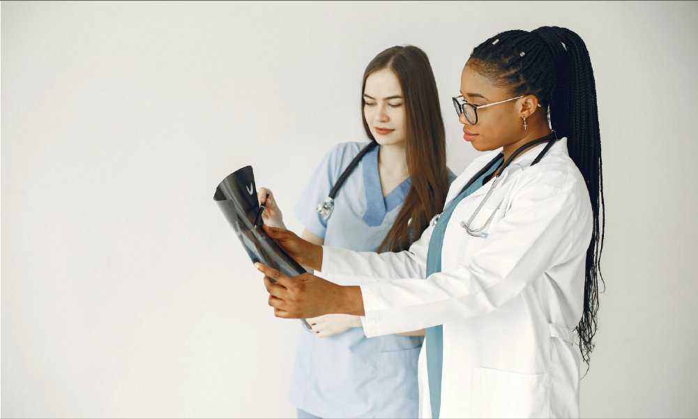 Dos doctoras analizando una radiografía en un centro médico para representar la consulta directa con especialistas mediante un seguro de salud privado en Colombia.