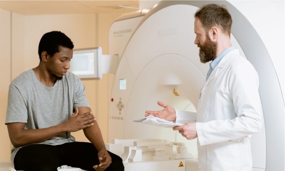 Médico especialista explicando un examen de resonancia magnética a un paciente para ejemplificar los diagnósticos incluidos en una póliza de salud o medicina prepagada.
