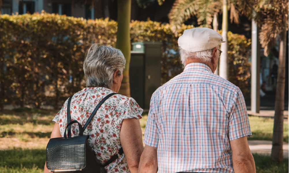 Pareja de adultos mayores caminando juntos al aire libre disfrutando de un retiro tranquilo y seguro.