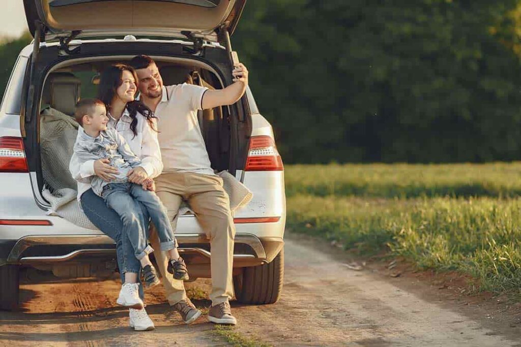 familia sentada en el baúl del carro